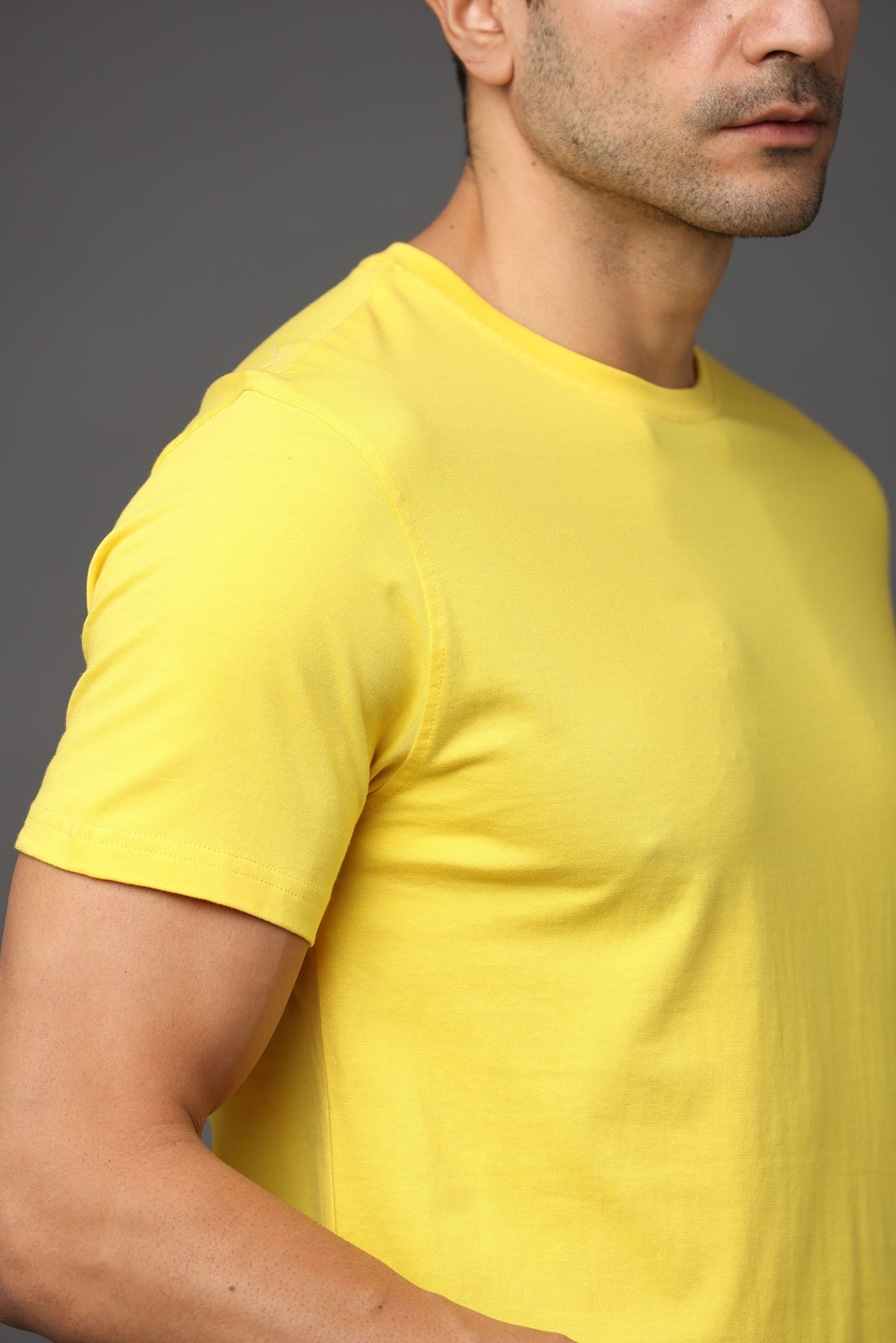 Man wearing a yellow t-shirt against a gray background