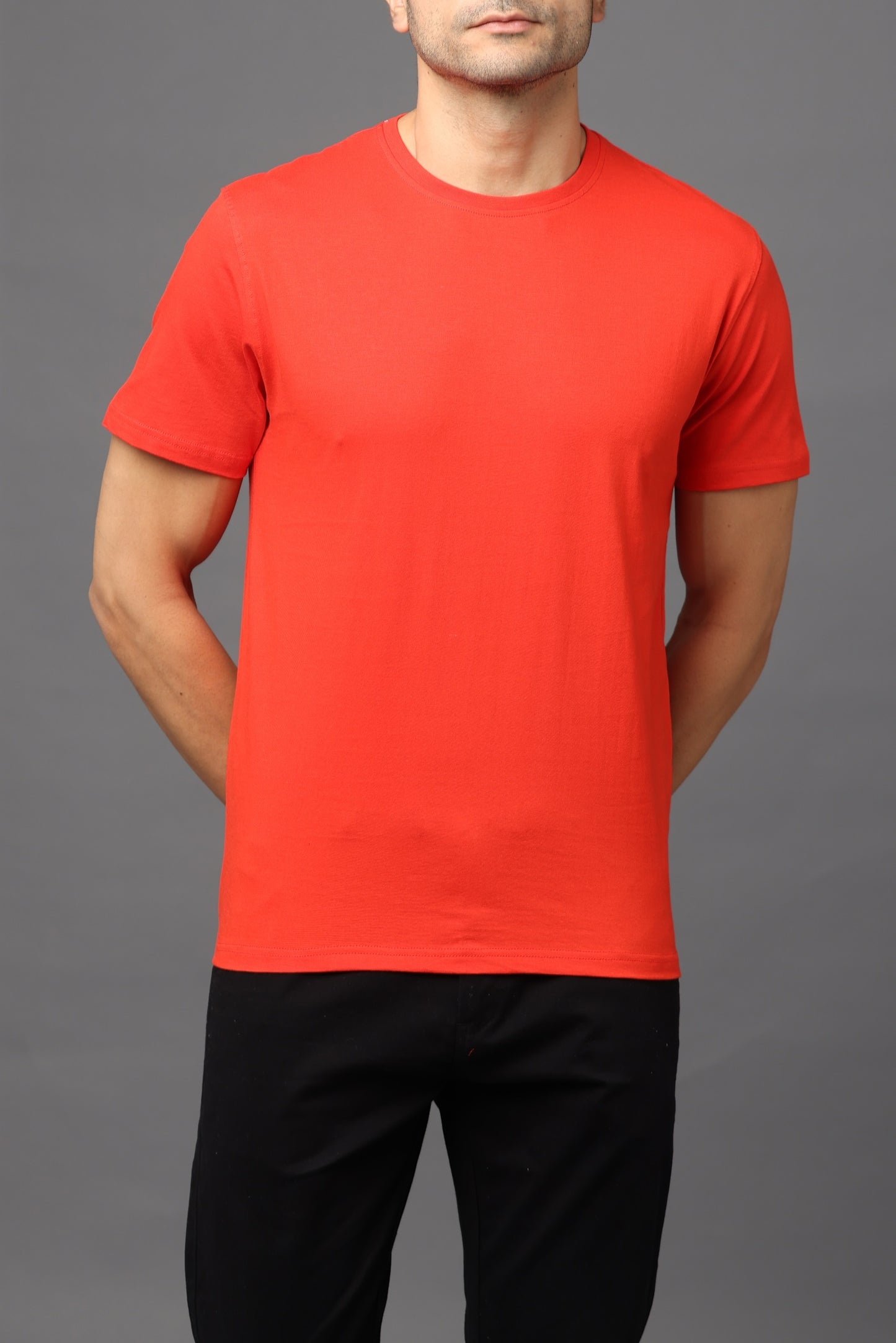 Person wearing a red t-shirt and black pants on a gray background